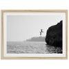 a black and white photo of a person jumping off a cliff into the water