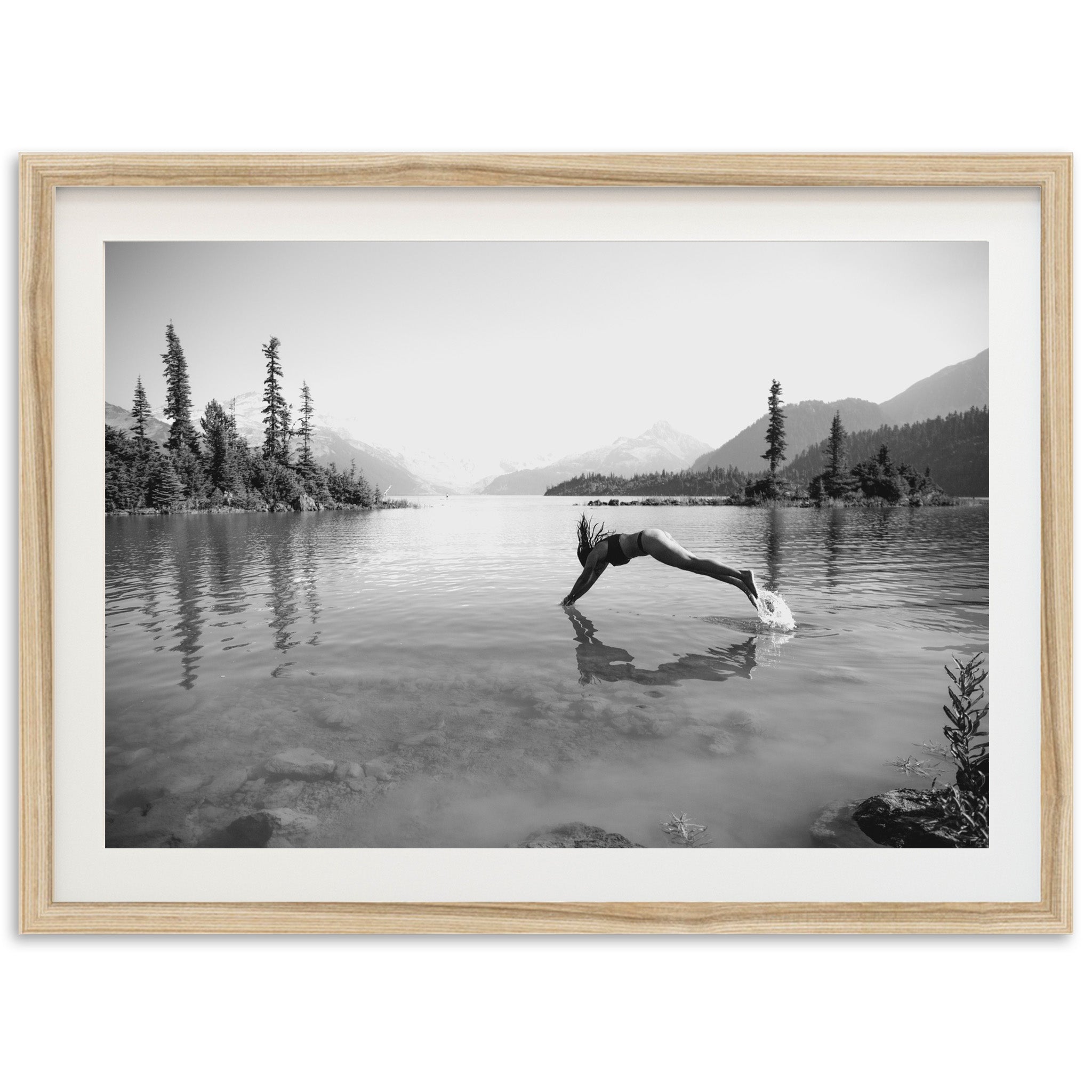 a black and white photo of a person diving into a lake