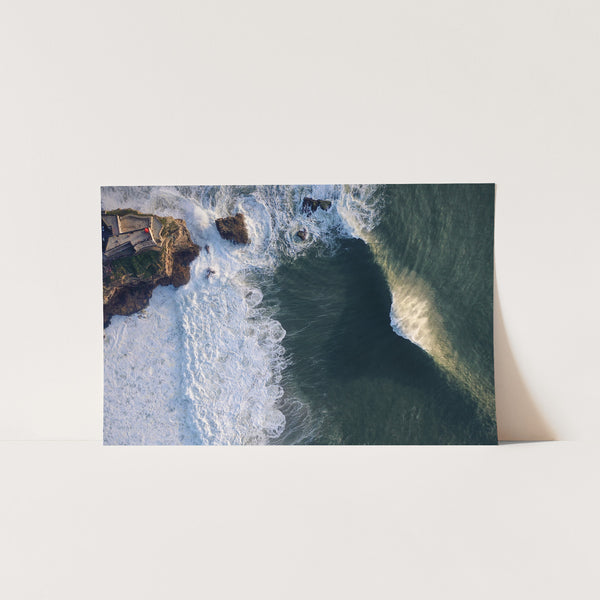 an aerial view of a wave crashing into the shore