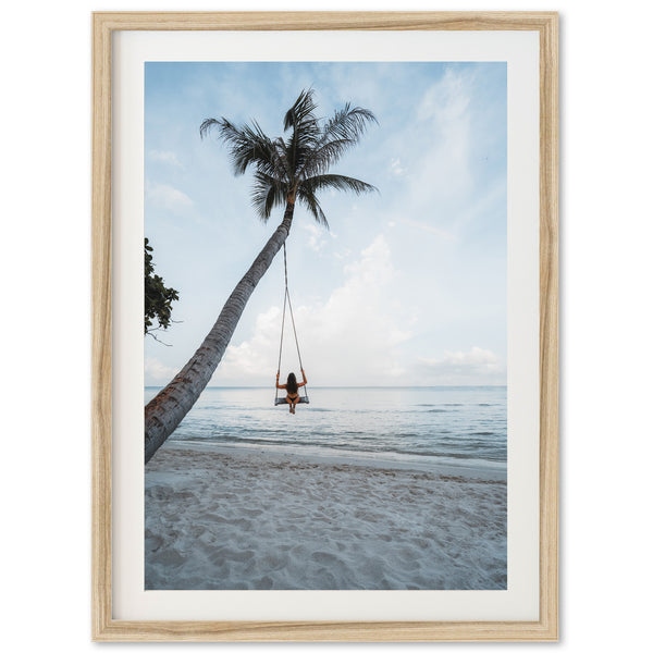 a person sitting on a swing between two palm trees