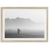 a black and white photo of a person carrying a surfboard